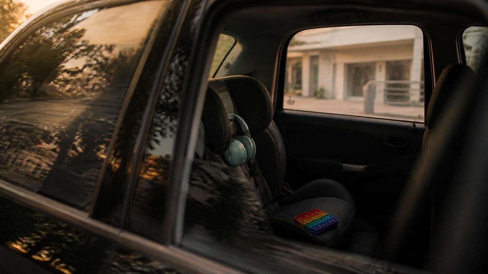Interior de carro com cadeirinha infantil e fone abafador de ruído, representando a rotina de deslocamento de uma criança autista às terapias.