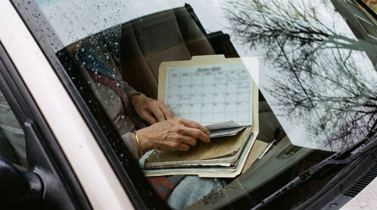 Mãe organiza documentos e agenda de terapias do filho dentro do carro.